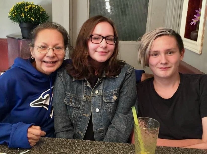 Two women and a young man sit at a table.