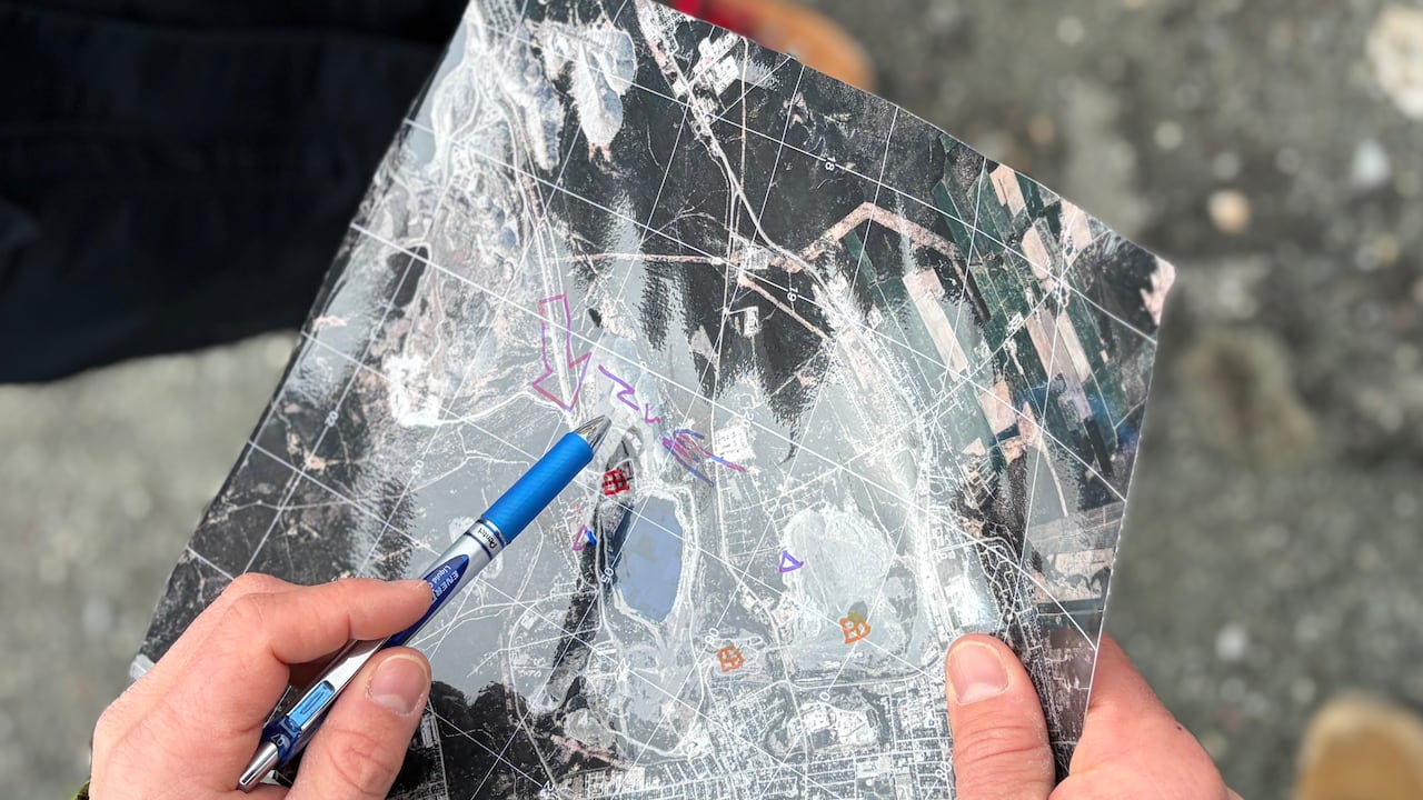 A person holds a map, circling sections of the map with a pen.