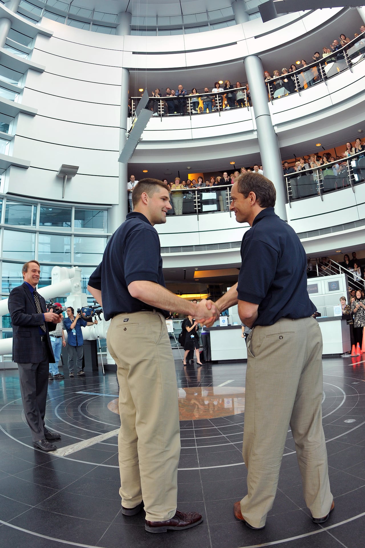 Two men are seen shaking hands in an auditorium.