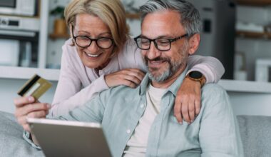 A happy older couple at home together, using tablet for online shopping.