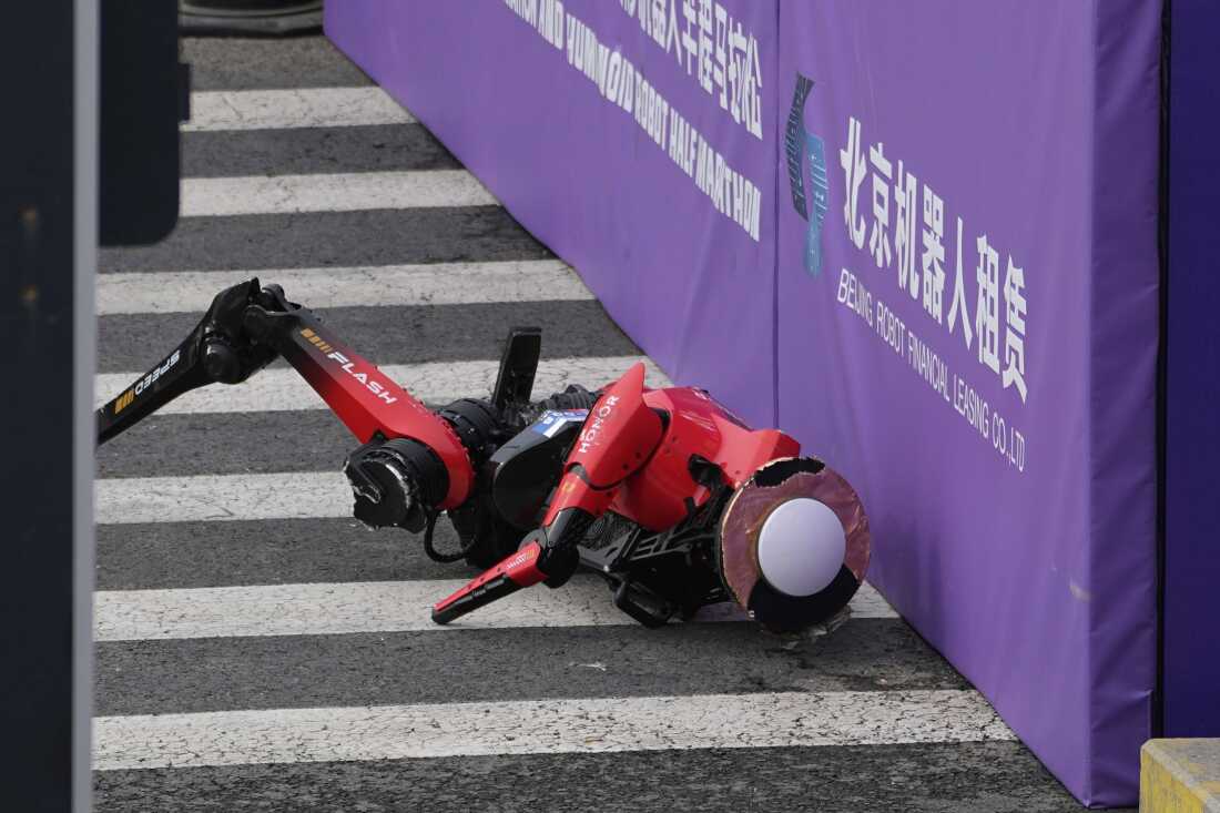 A robot crashes against a board after crossing the finish line in the Beijing E-Town Half Marathon and Humanoid Robot Half-Marathon held in the outskirts of Beijing, Sunday, April 19, 2026.