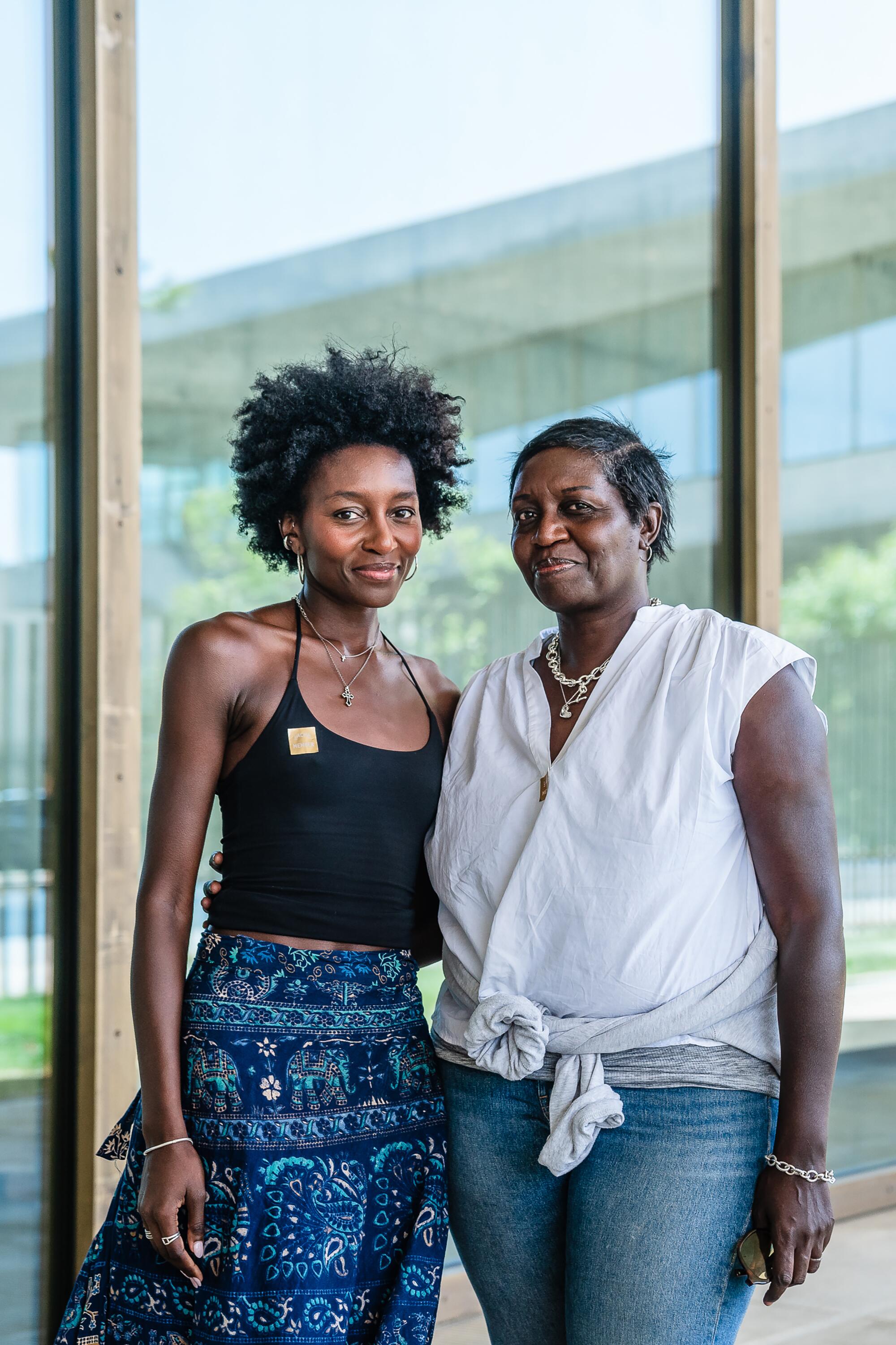 Two women stand in front of the glass wall on the ground floor of a museum.