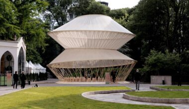 Garden setting with the yurt pavilion surrounded by trees and visitors walking nearby