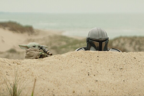 This image released by Disney shows The Mandalorian, portrayed by Pedro Pascal, right, and Grogu in a scene from Lucasfilm's "The Mandalorian and Grogu." (Lucasfilm Ltd. - Disney via AP)