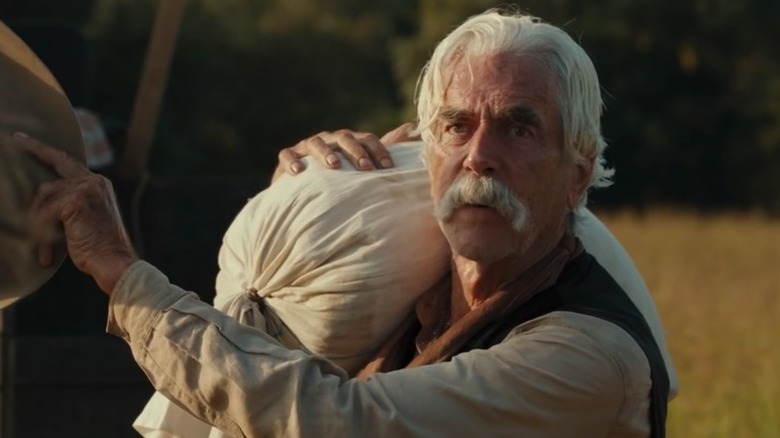 Shea Brennan (Sam Elliott) looks up emotionally while carrying a sack in 1883