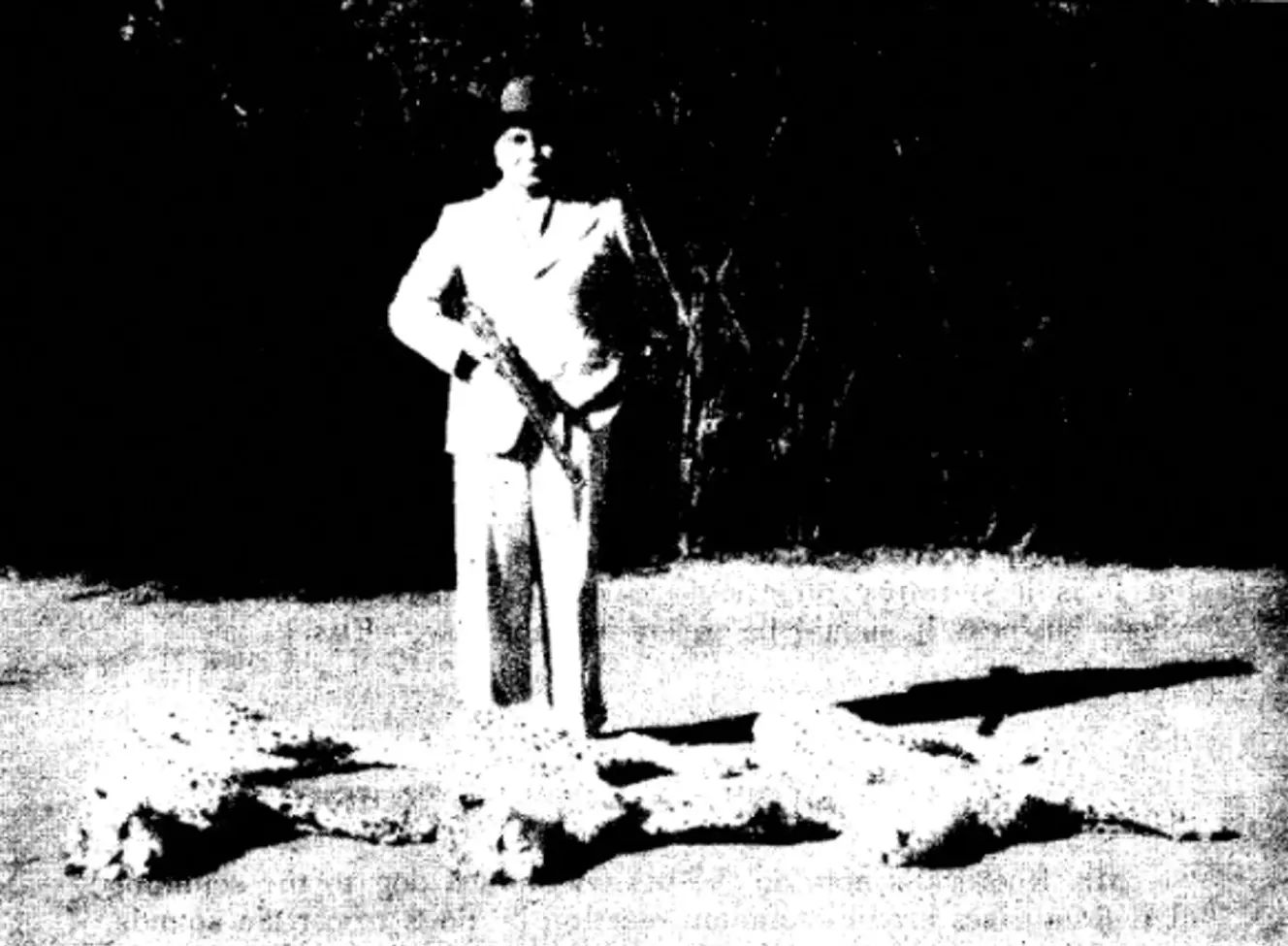 Maharajah Ramanuj Pratap Singh Deo stands with a rifle next to three cheetahs he killed.