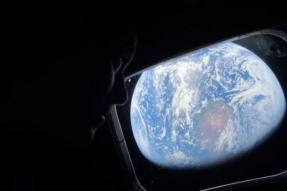 Commander Reid Wiseman looks at the Earth from a window aboard the Orion spacecraft Integrity during the Artemis II mission en route to the moon.