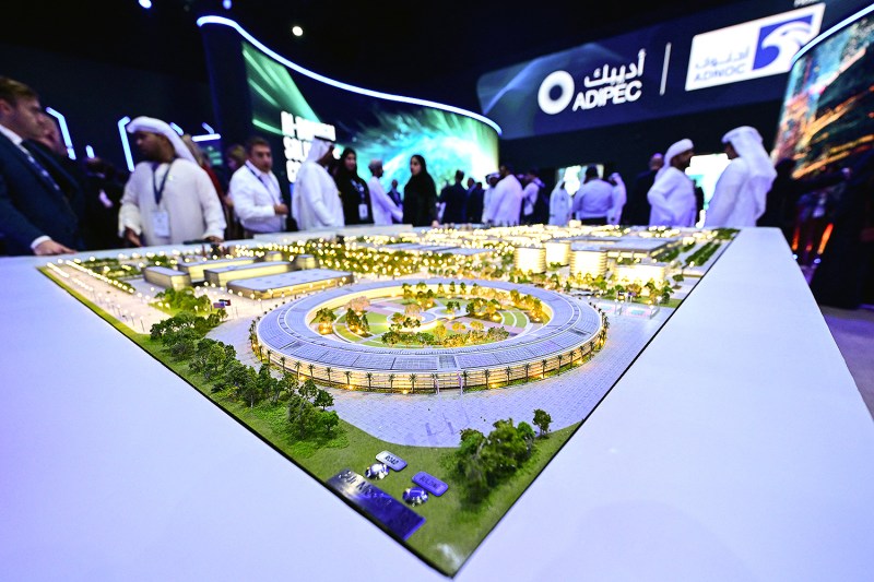 People gather around a table that shows a miniature model of a data center complex.