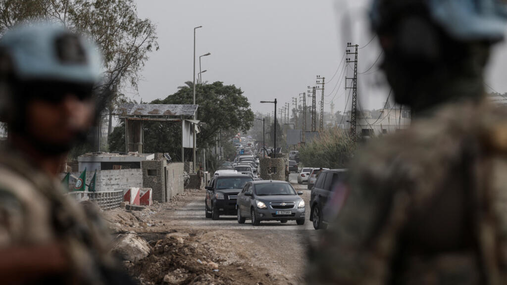 UN peacekeepers stand guard, as displaced people make their way back to their homes after crossing the bridge linking southern Lebanon to the rest of the country.