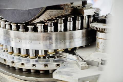 Background shot of punch tools in tablet press machine compressing powder into pills at pharmaceutical manufacturing plant