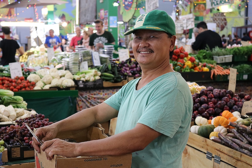 A man in a green cap in a fruit store.