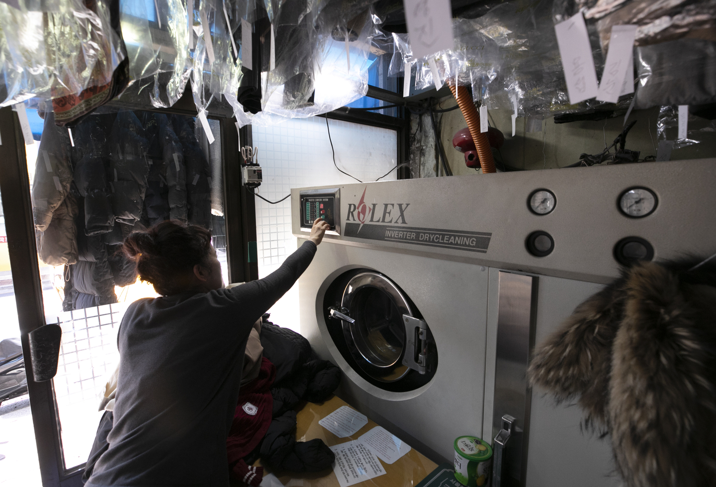 A laundry shop owner operates a dry-cleaning machine at the shop in Seoul on April 19, 2023. [NEWS1]