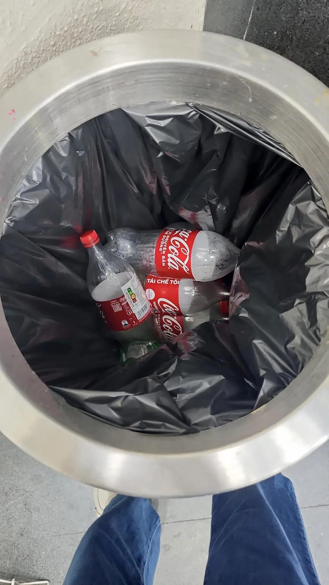 The man threw the empty 1.5 litre coke bottles into a rubbish bin.