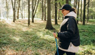 Woman doing metabolic walking holding pole and walking through forest wearing activewear and cap with coat on