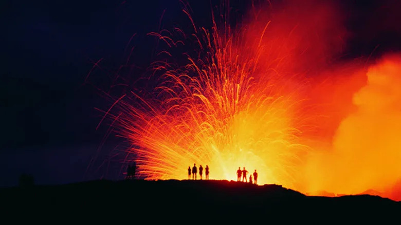 Group of people standing in front of volcanic eruption
