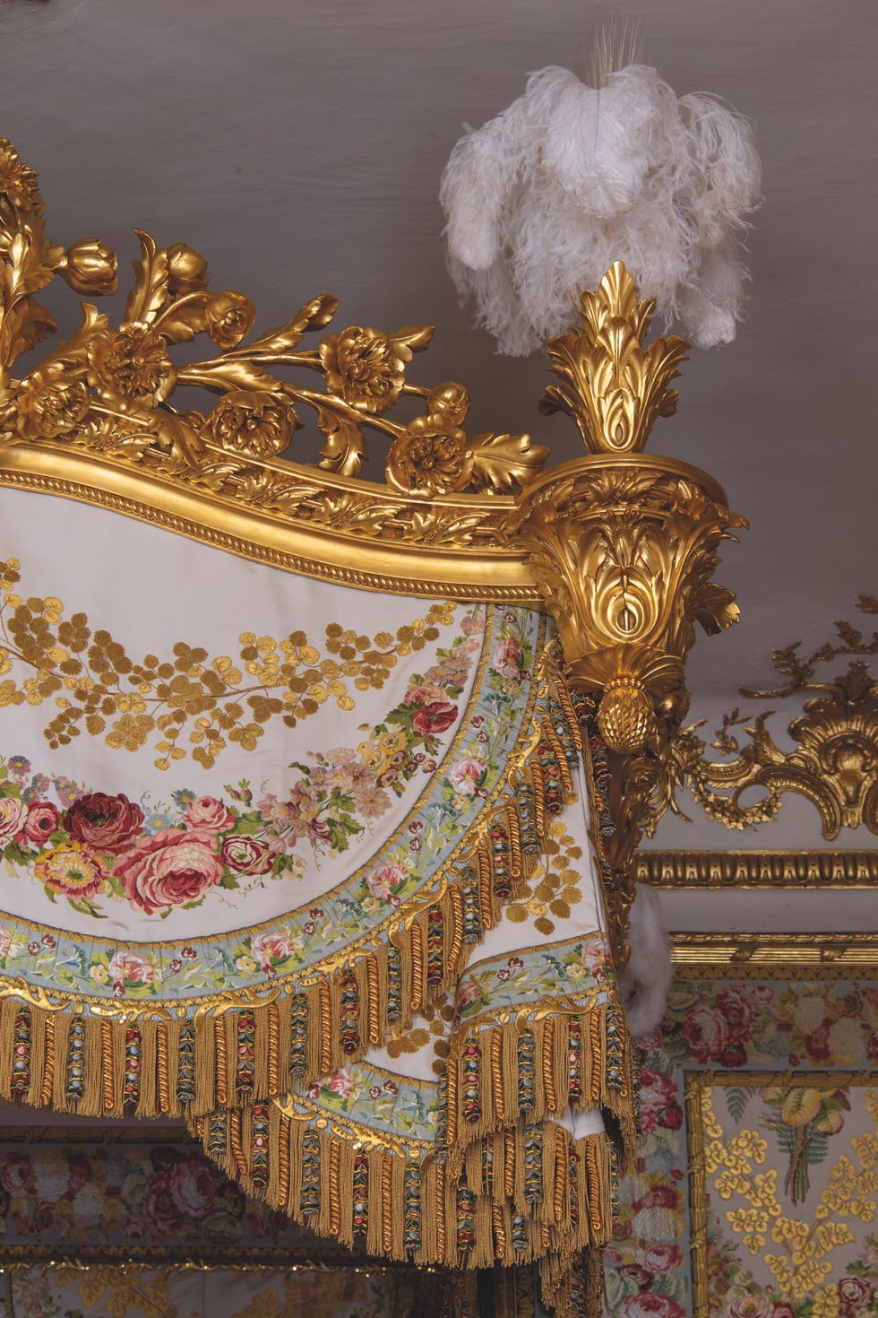 Ornate bed canopy with floral decorations and gold embellishments.