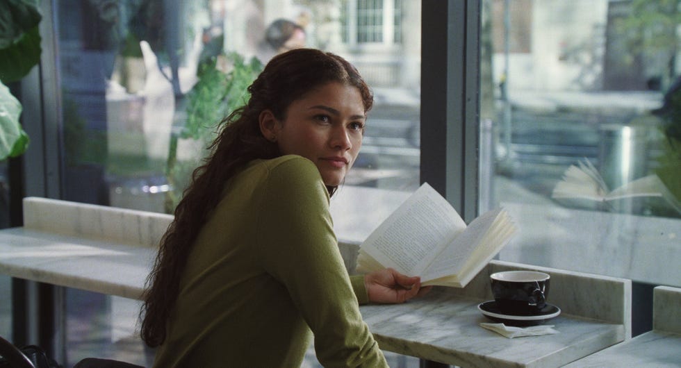 Person reading a book in a café setting with a coffee cup on the table.
