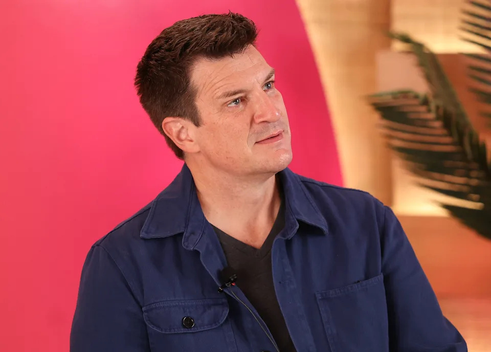 Person in a blue jacket with a thoughtful expression, seated indoors