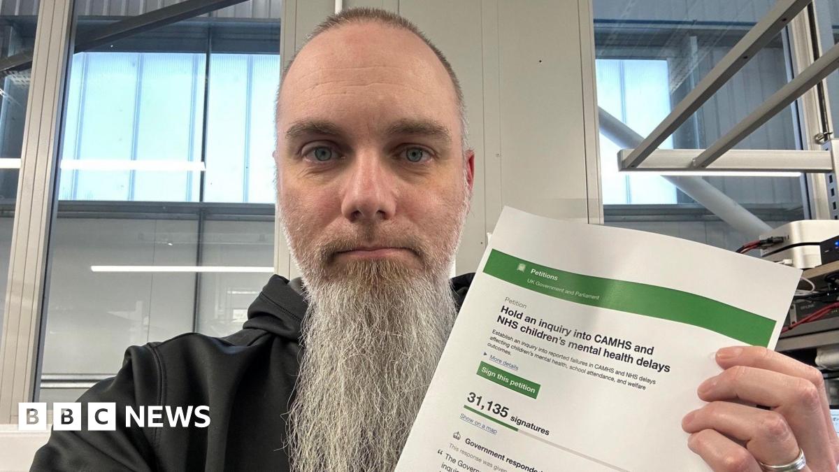Tom is holding a petition in his hands and wearing a black hoodie.