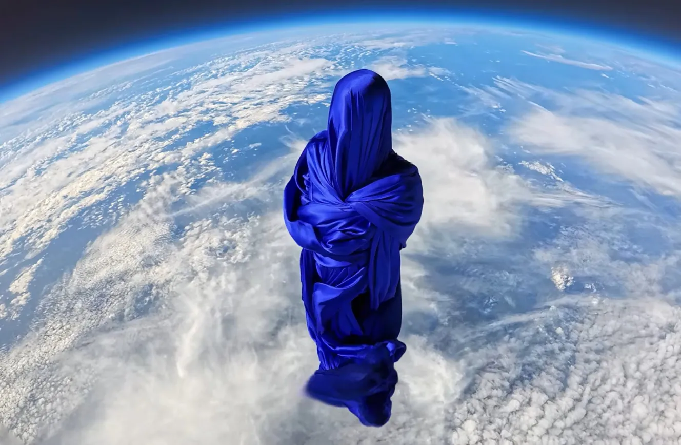 A silk-covered mannequin in the stratosphere with Earth and clouds in the background.