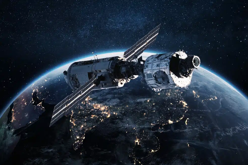 Satellite,orbiting,earth,at,night,with,glowing,city,lights,below.