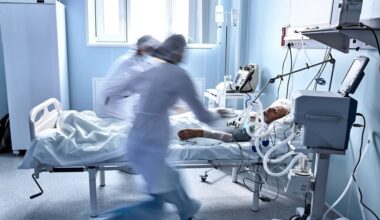 Physician and medical team providing urgent care to an elderly patient in a modern hospital ward ICU.