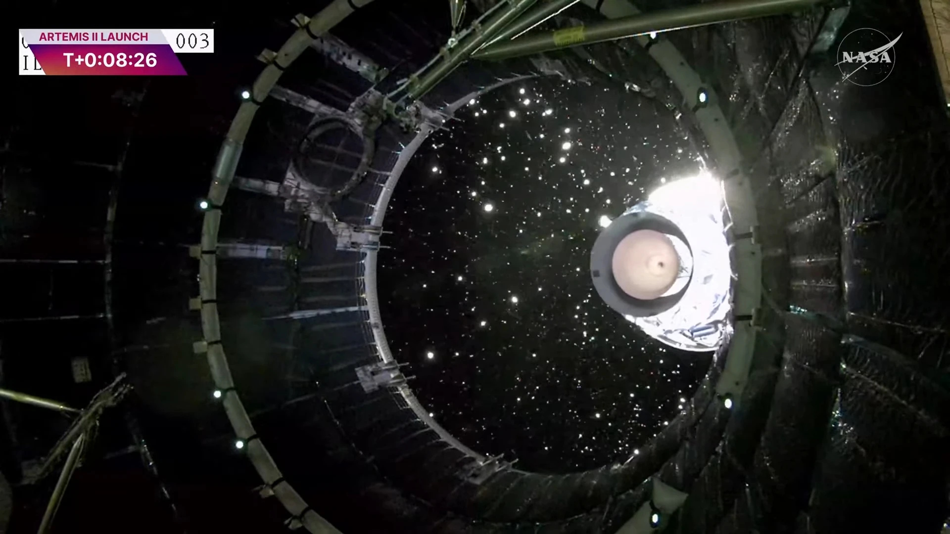 View from inside a spacecraft showing stage separation during the Artemis I launch, with debris and stars shining against space’s blackness. The NASA logo and launch timer are displayed, capturing the hope of Artemis II's journey to the Moon and back to Earth.