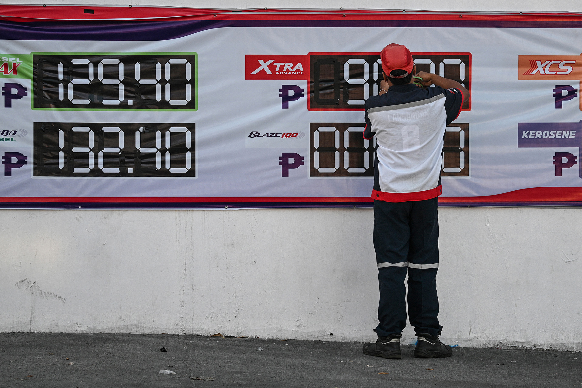 An employee changes the price signage of fuel at a petrol station in San Fernando, Pampanga province on April 3, 2026.