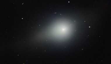 A large white fuzzy object, 3I/ATLAS, with a short tail in black space with small a few stars.