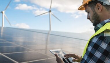 A worker on a solar power plant looking at a tablet.