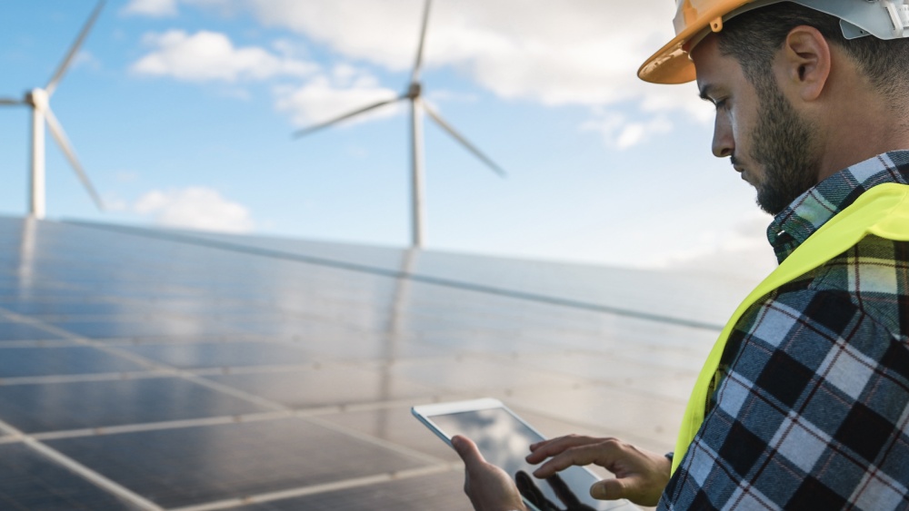 A worker on a solar power plant looking at a tablet.
