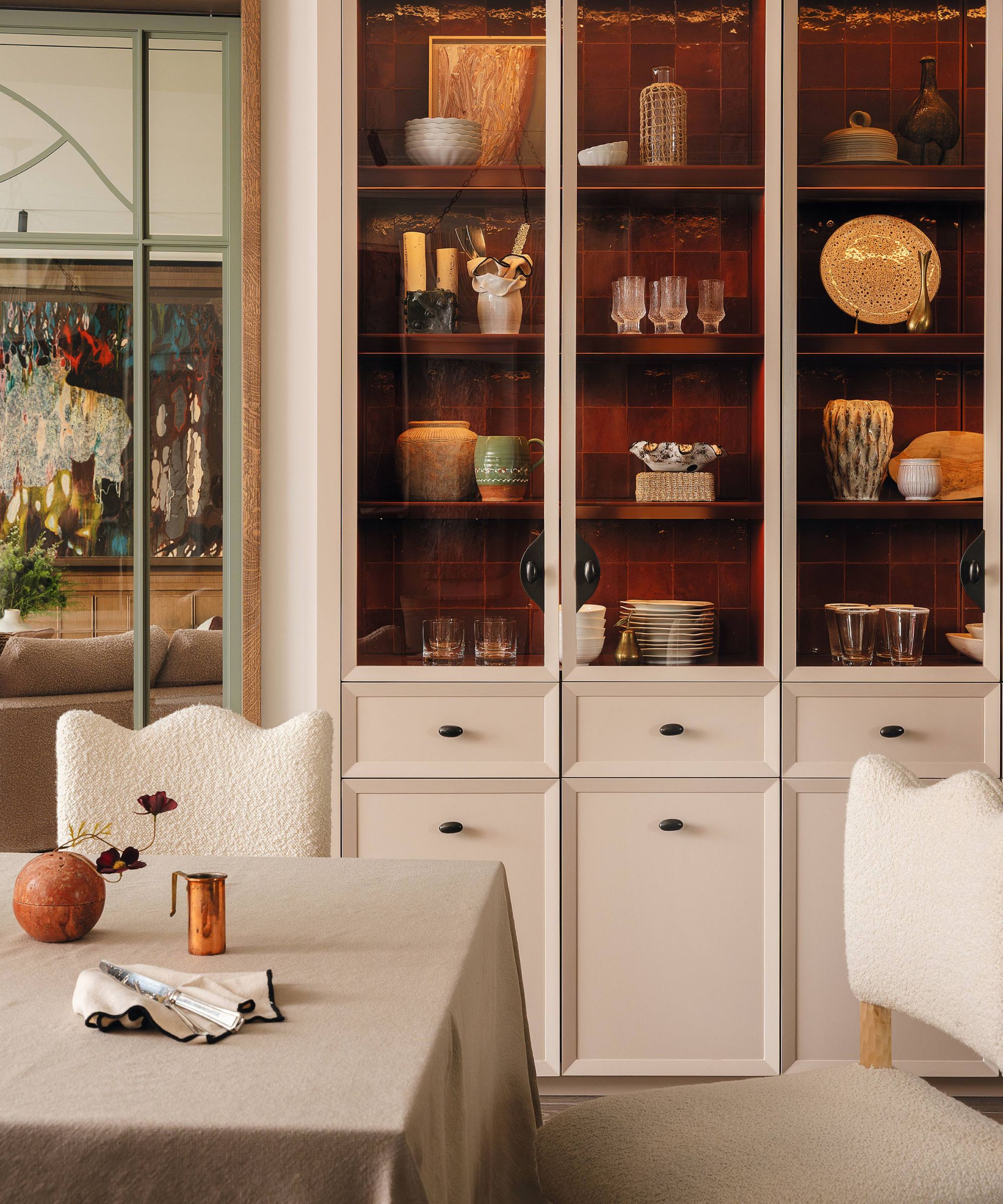 a dining room with soft pink neutral cabinetry tiled inside with dark red zellige tiles