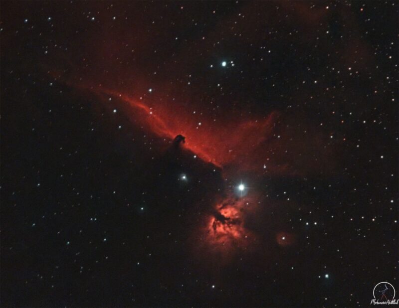 Streaky red space clouds among stars, with a small dark indentation resembling the head of a horse.