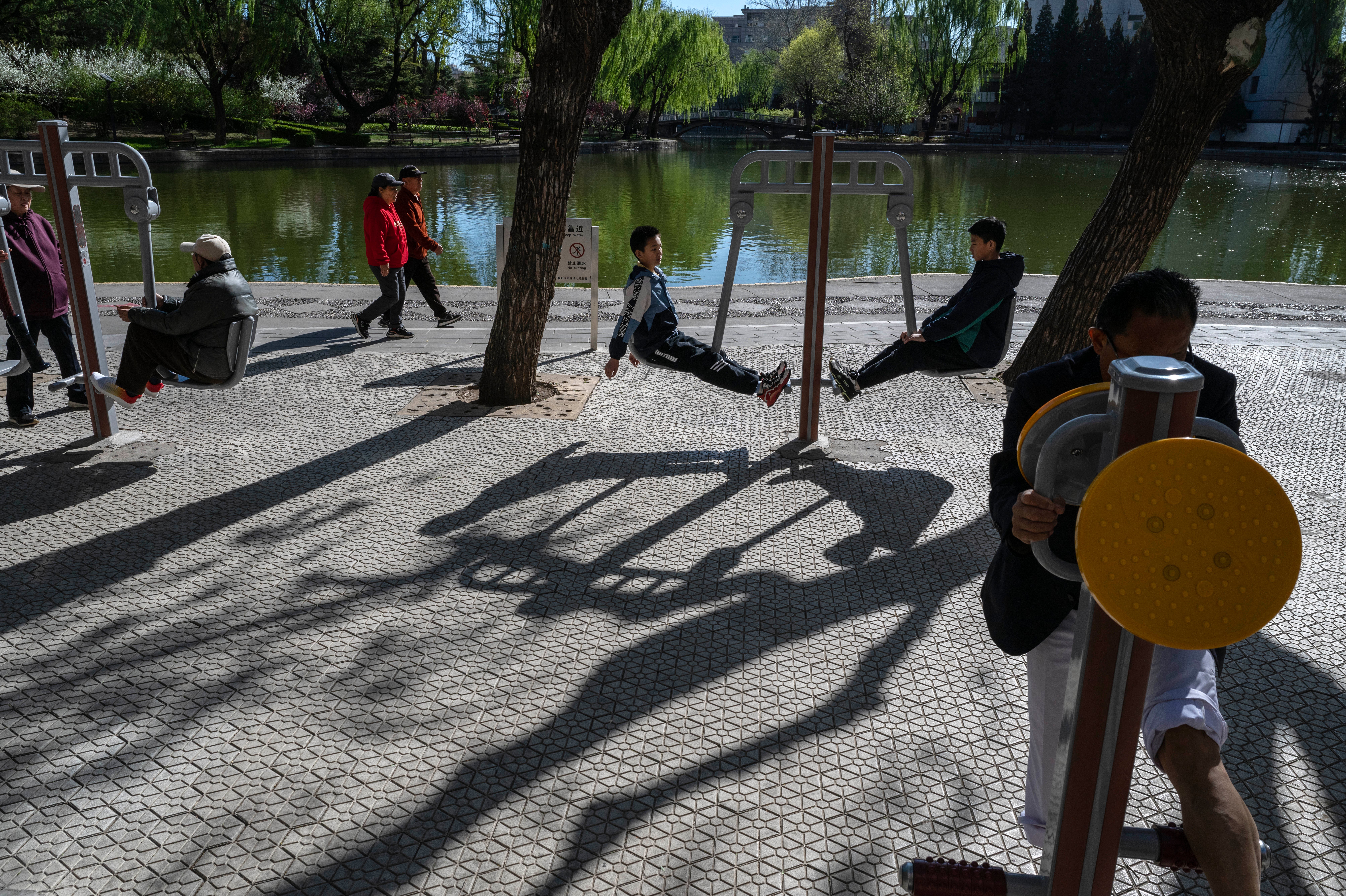 People exercise on public fitness equipment at a park on April 6, 2026 in Beijing, China