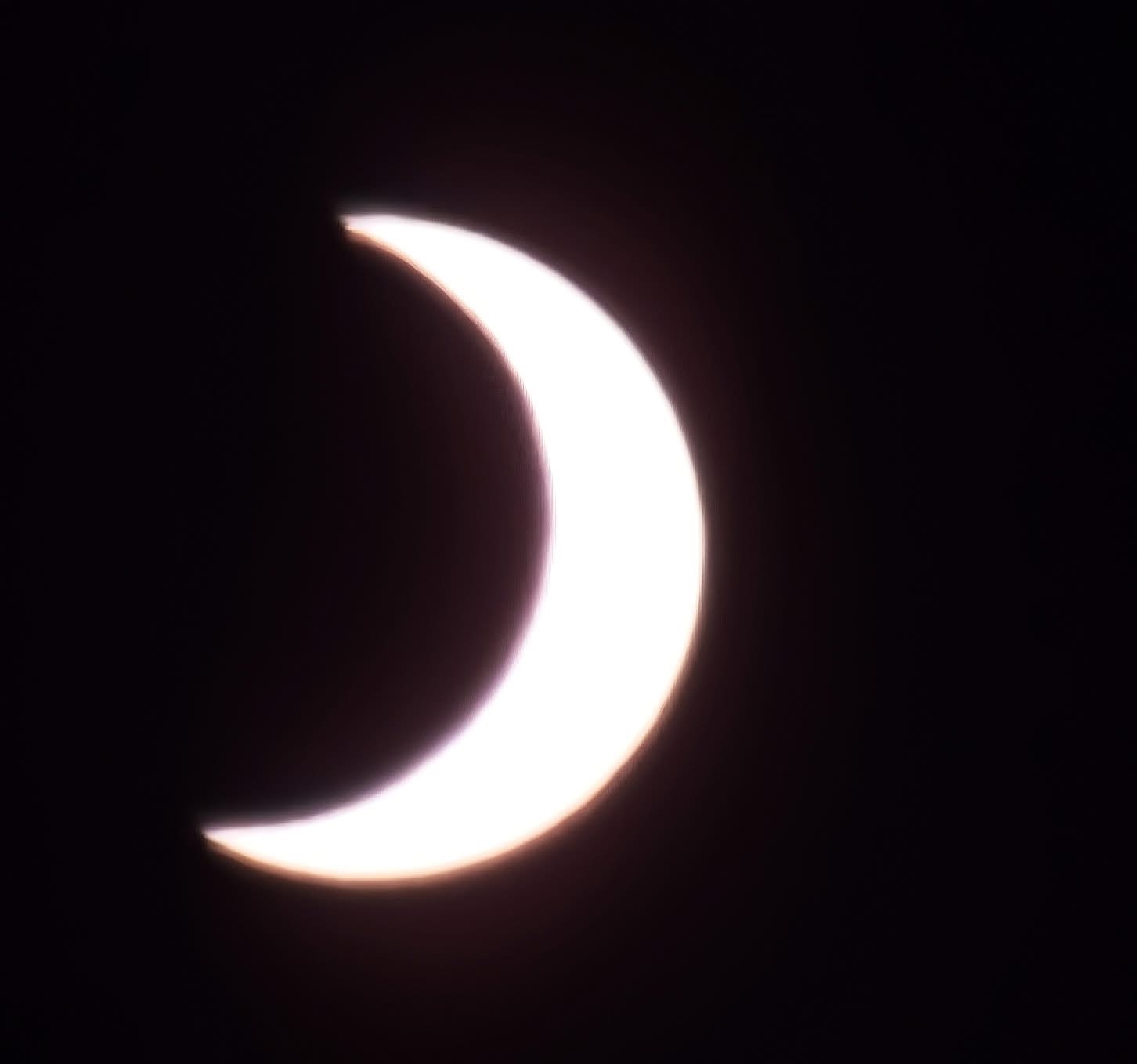 close up view of the sun appearing as a crescent as the moon starts to cover it.