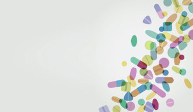 Abstract illustration of colorful pills and capsules scattered diagonally across a light background to illustrate that switching medicine formulation for children has significant cost savings