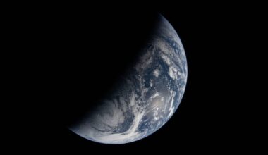 A crescent view of Earth from space, with one side illuminated by sunlight and the other in shadow, showing blue oceans, white clouds, and portions of continents against a black background.