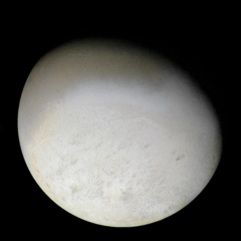 Image of Neptune's moon Triton with varied textures on a pale surface.