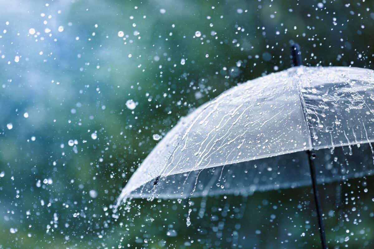 Transparent umbrella under heavy rain against water drops splash background.