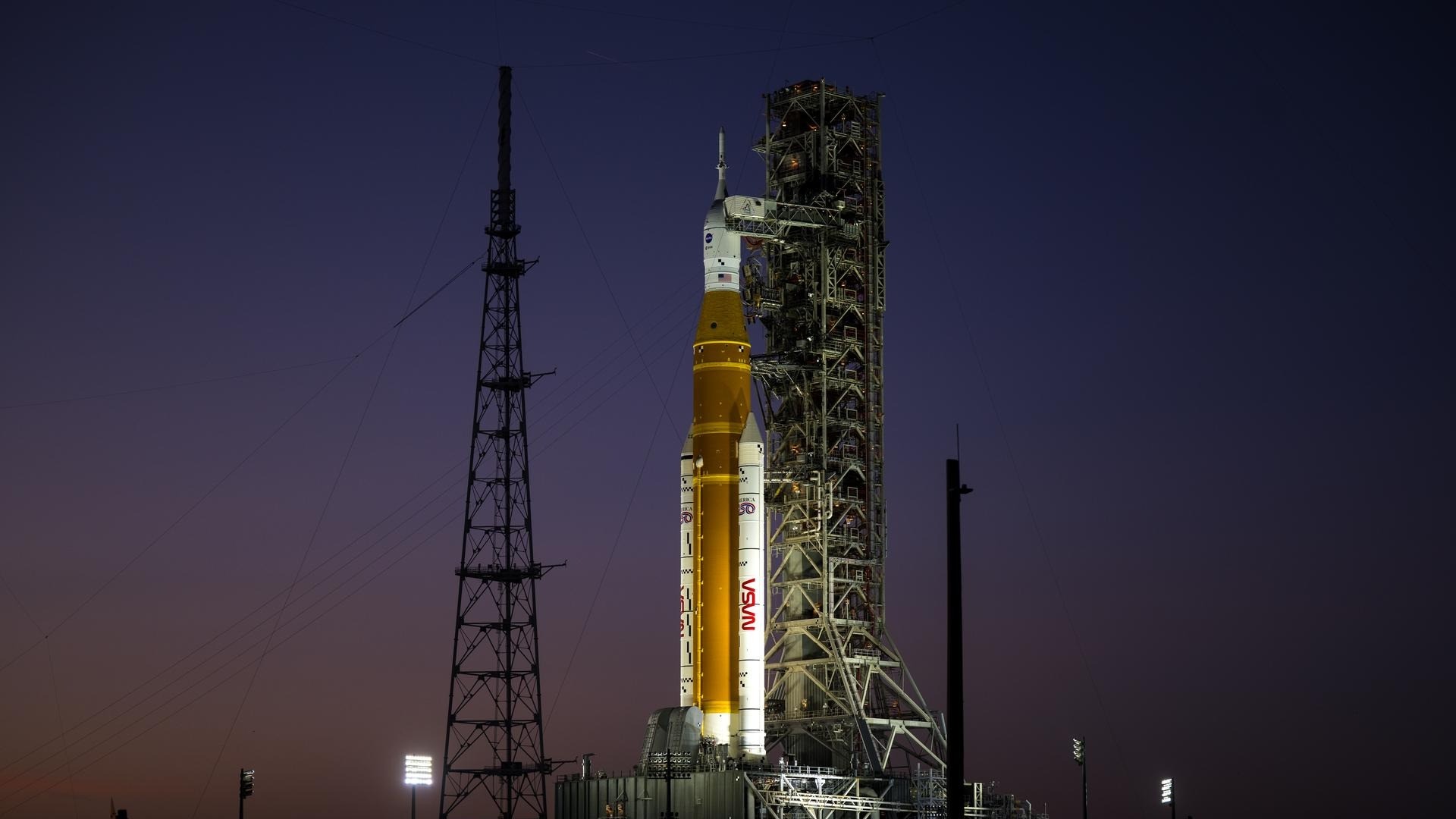 an orange rocket on a launch pad at sunset