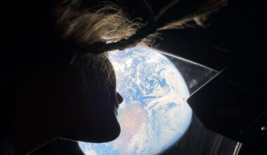 The silhouette of a woman looking out the window at Earth.