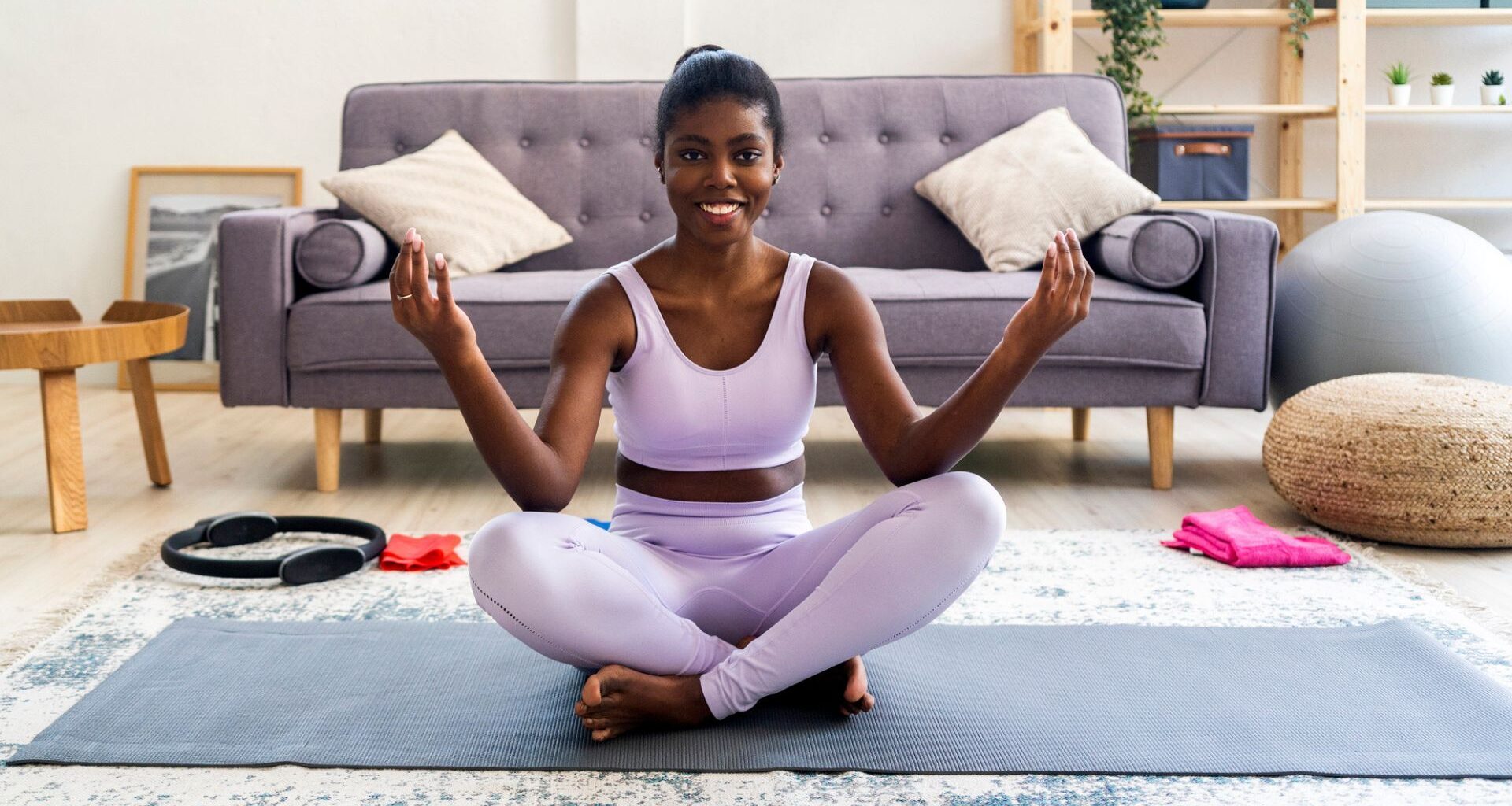 woman sits cross-legged on yoga mat