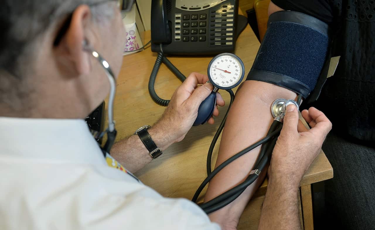 A doctor checks a patient's blood pressure in an office.