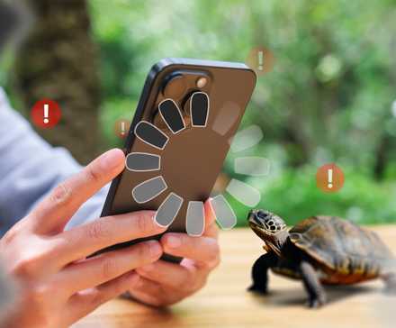 A person holding an iPhone with a loading icon and a turtle next to it, with some warning signs around.