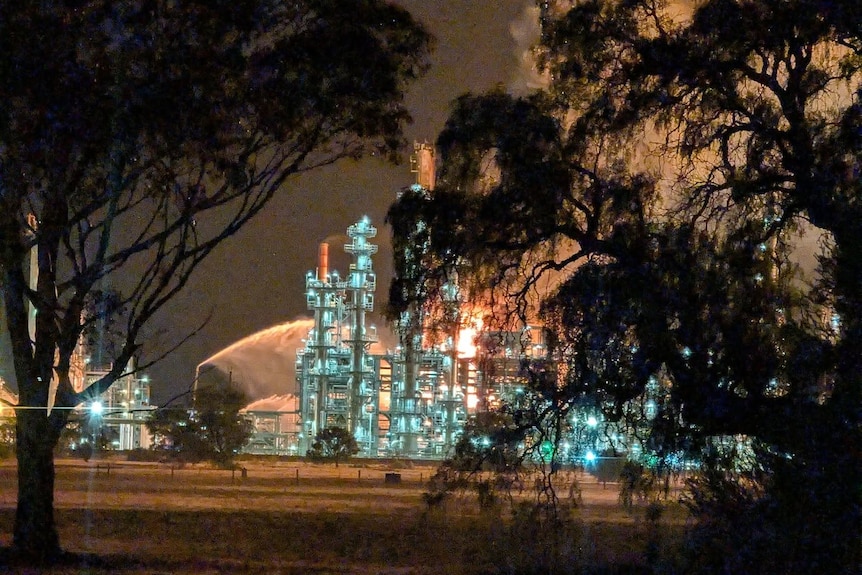 Smoke rises from an industrial site at night.