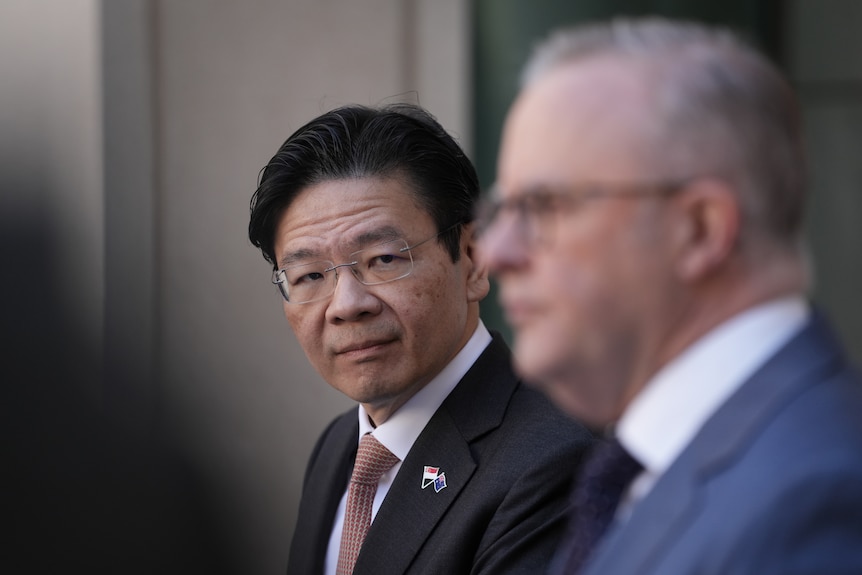 A man looks at another man during a press conference