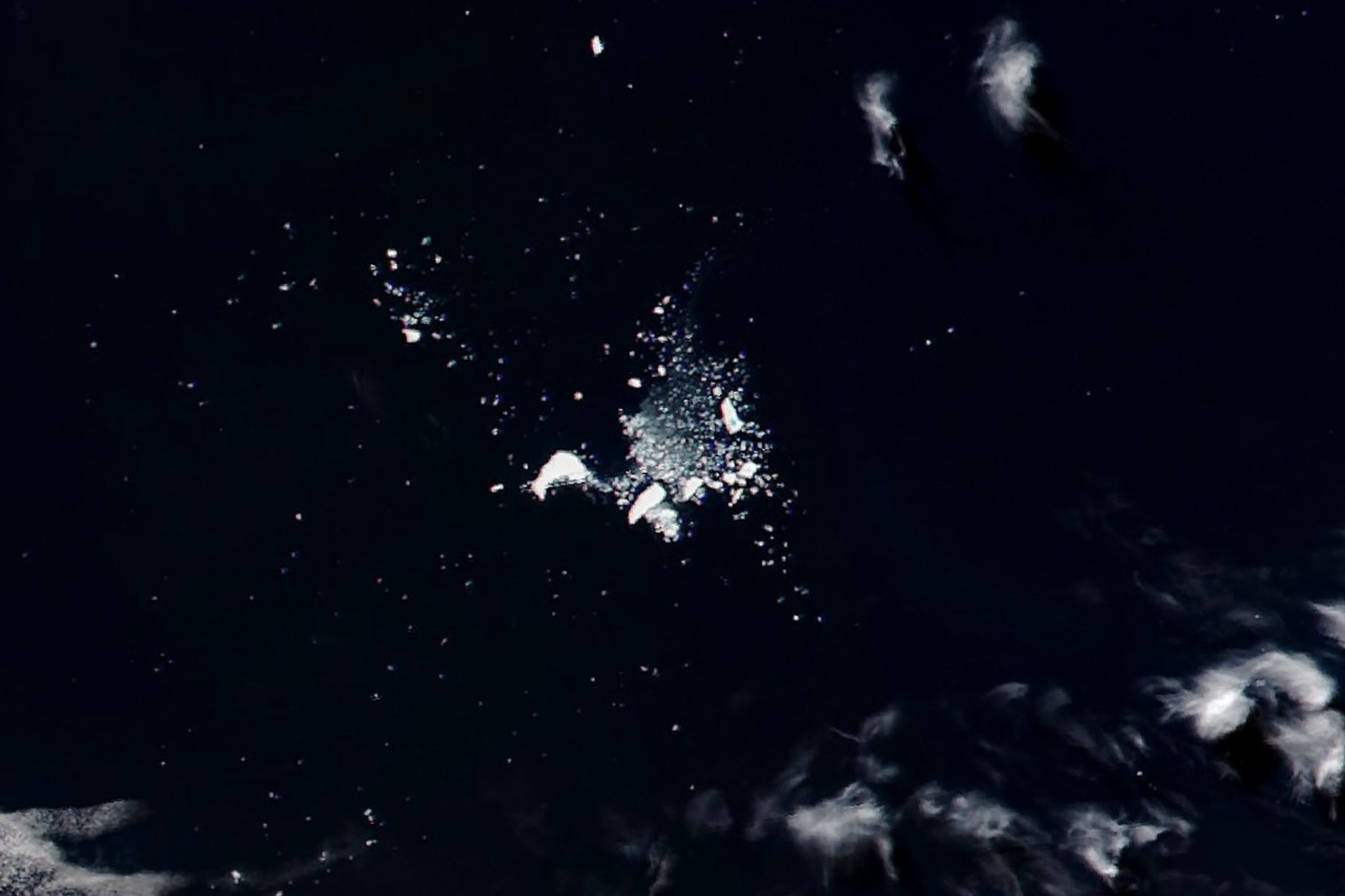 Two stacked images: the top shows a massive, newly formed iceberg near Antarctica; bottom shows the same iceberg 40 years later in the South Atlantic, fragmented into many small pieces.