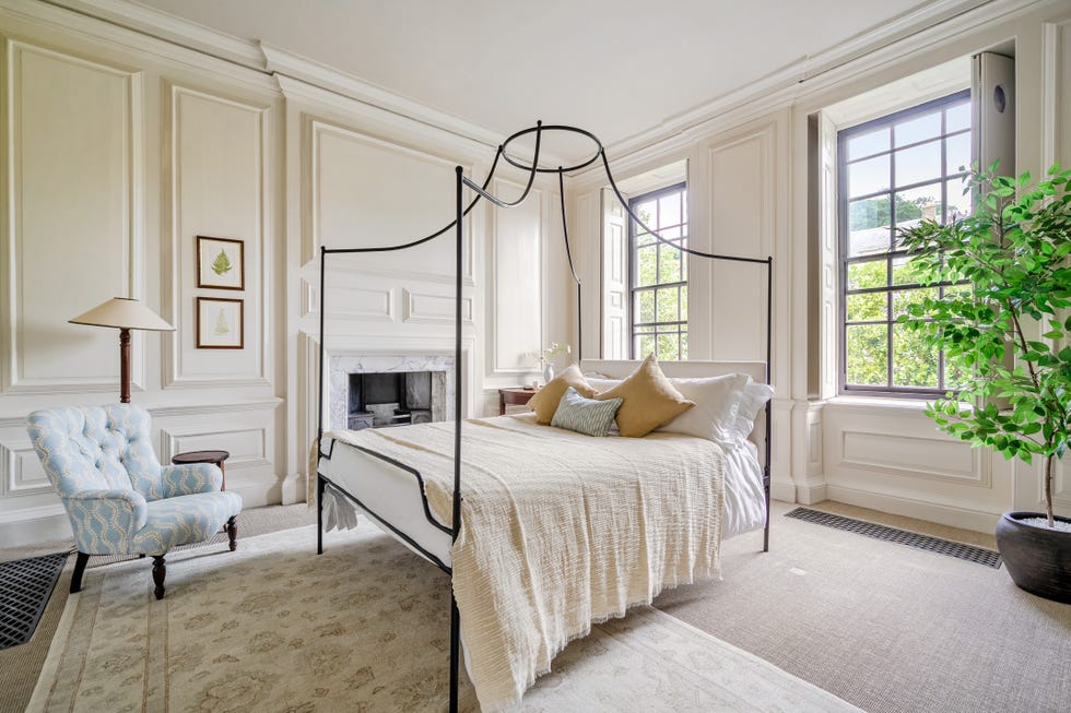Cozy bedroom featuring a metal canopy bed, armchair, and large windows.