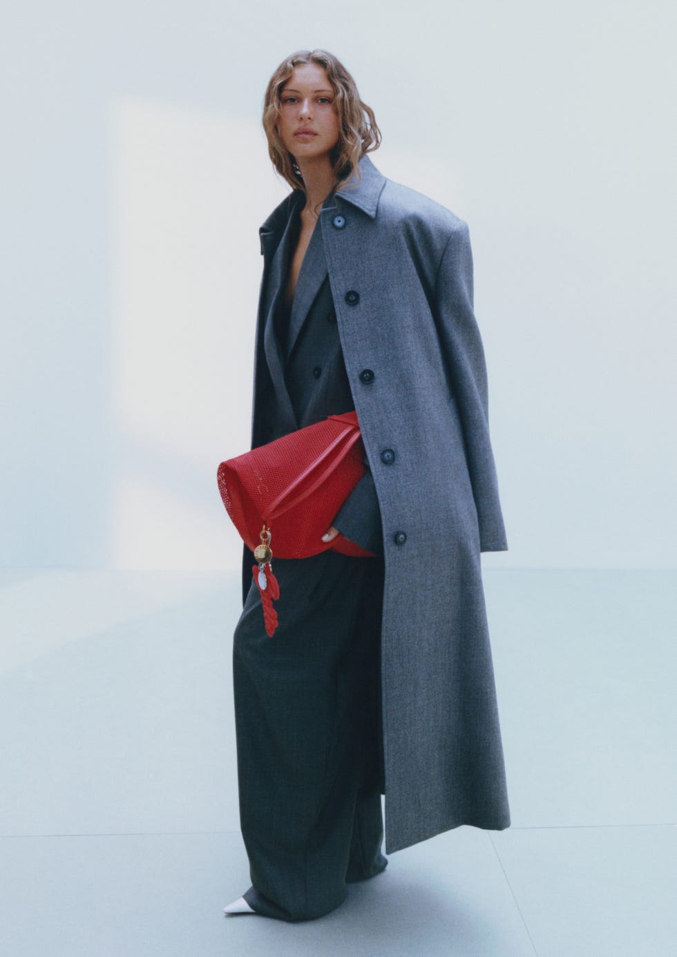 person wearing a stylish gray coat and carrying a red bag