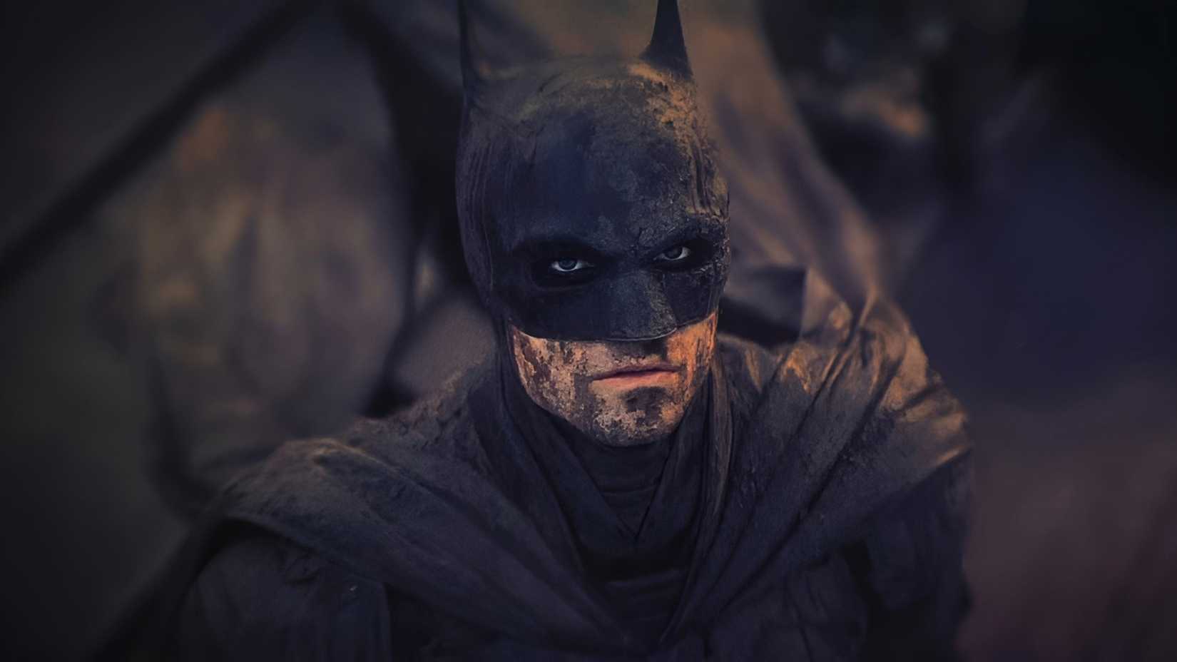 Robert Pattinson's Batman with dirt all over his face and suit looking up in The Batman